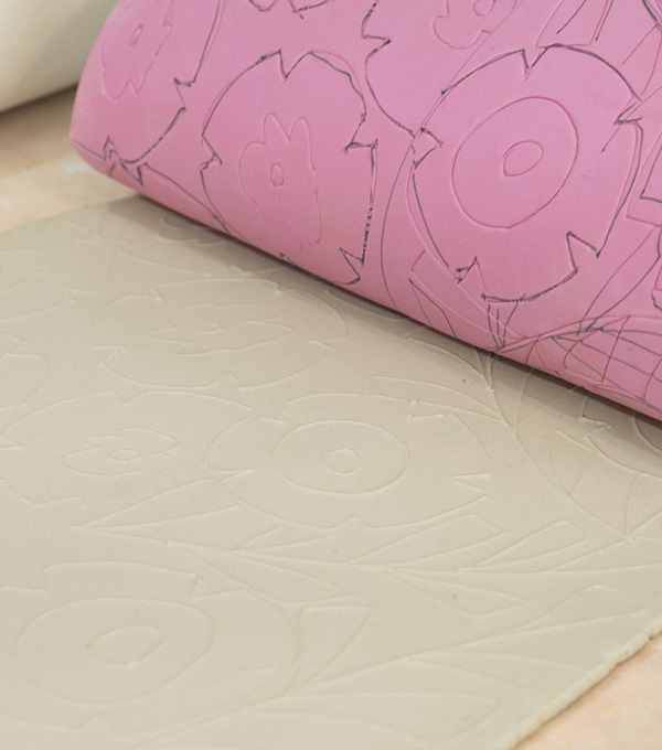 2 Roll out clay on a slab roller. Place the craft foam on top of the clay and roll it again, transferring the pattern to the clay.