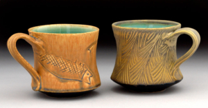 two gold glazed mugs with turquoise glaze on the inside
